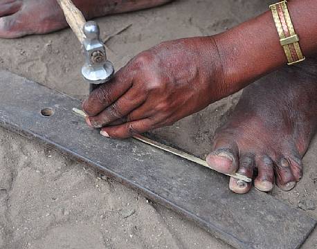 Fine mønstre bankes ud i gammelt kobber. Læg mærke til mandens armbånd