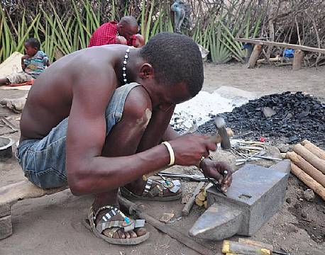 Datoga smeden hamrer pilespidser ud af gamle knive og andet affaldsmetal